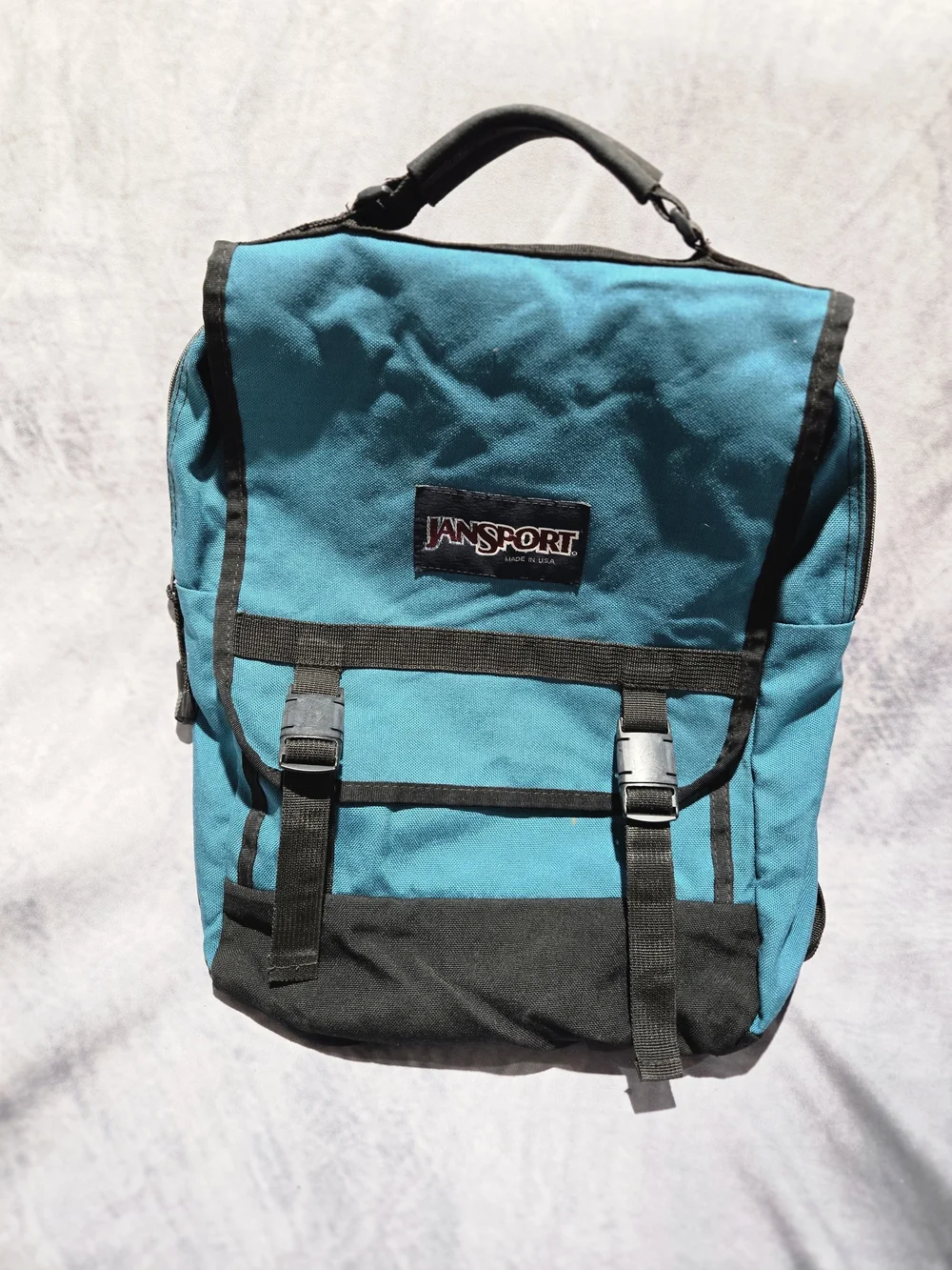 vintage 1990s turquoise and black JanSport canvas backpack featuring a top flap